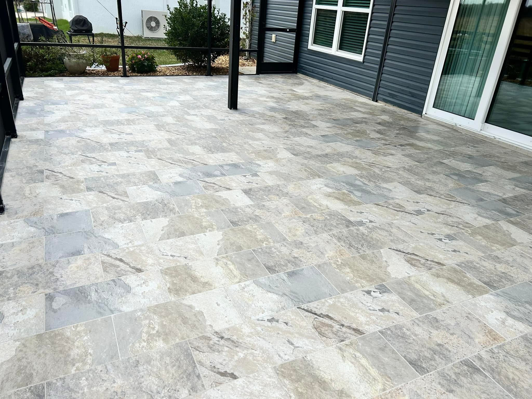 Resort-style luxury at home. A stunning large-format silver travertine-style tile installation that completely elevates this open-air patio.