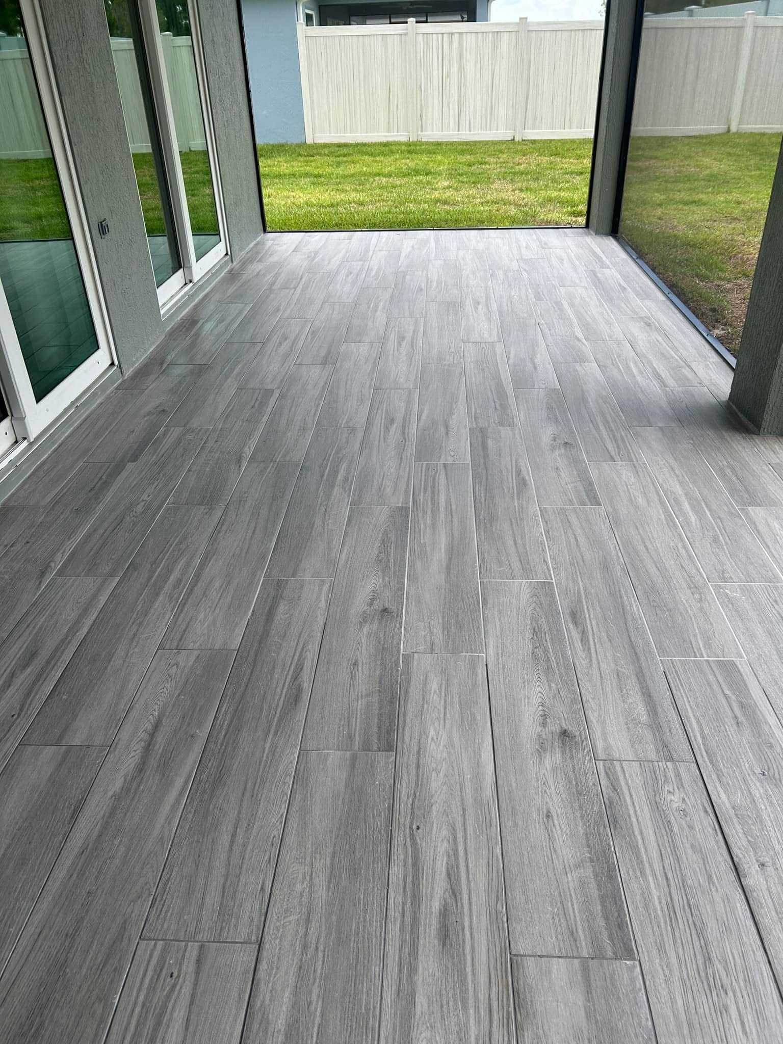 This high-end porcelain plank installation brings an elegant indoor hardwood feel to the outdoors, perfectly matching modern cool-toned home exteriors.