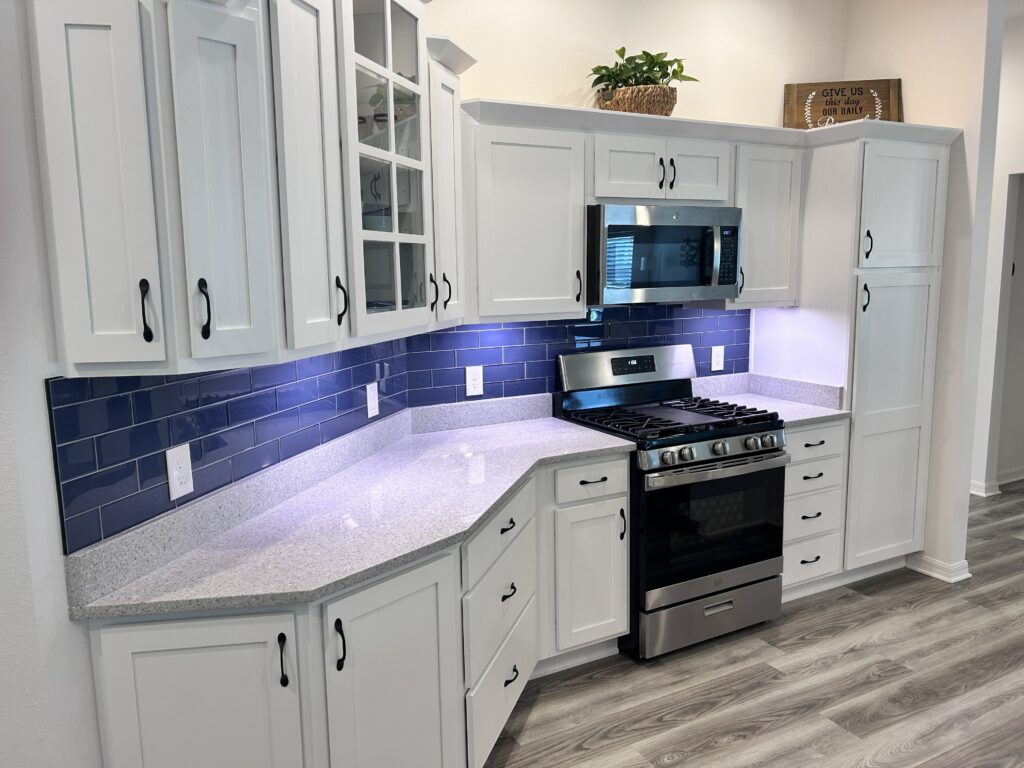 Custom blue subway tile kitchen backsplash installation by CRB Services Pro in The Villages, FL. Modern kitchen featuring white cabinets, granite countertops, and professional tile craftsmanship.