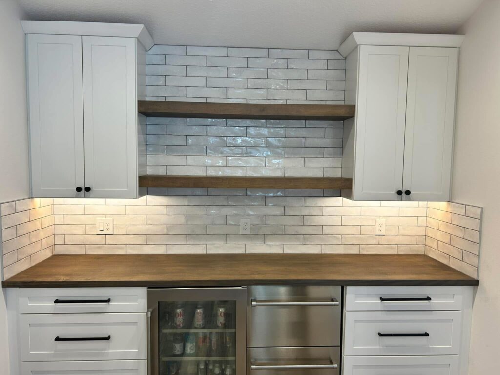 Timeless design meets modern functionality. Glossy white subway tile with contrasting grout perfectly pairs with rustic open wood shelving.