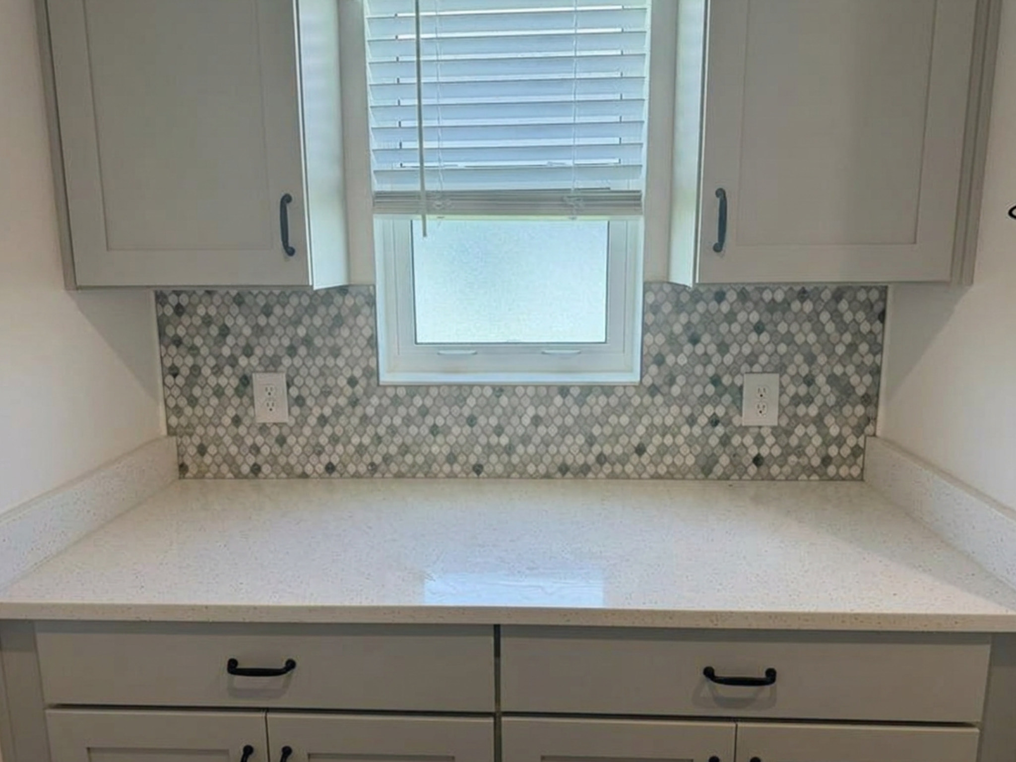 Laundry room window nook featuring custom-cut gray and white honeycomb geometric mosaic tile backsplash installation.