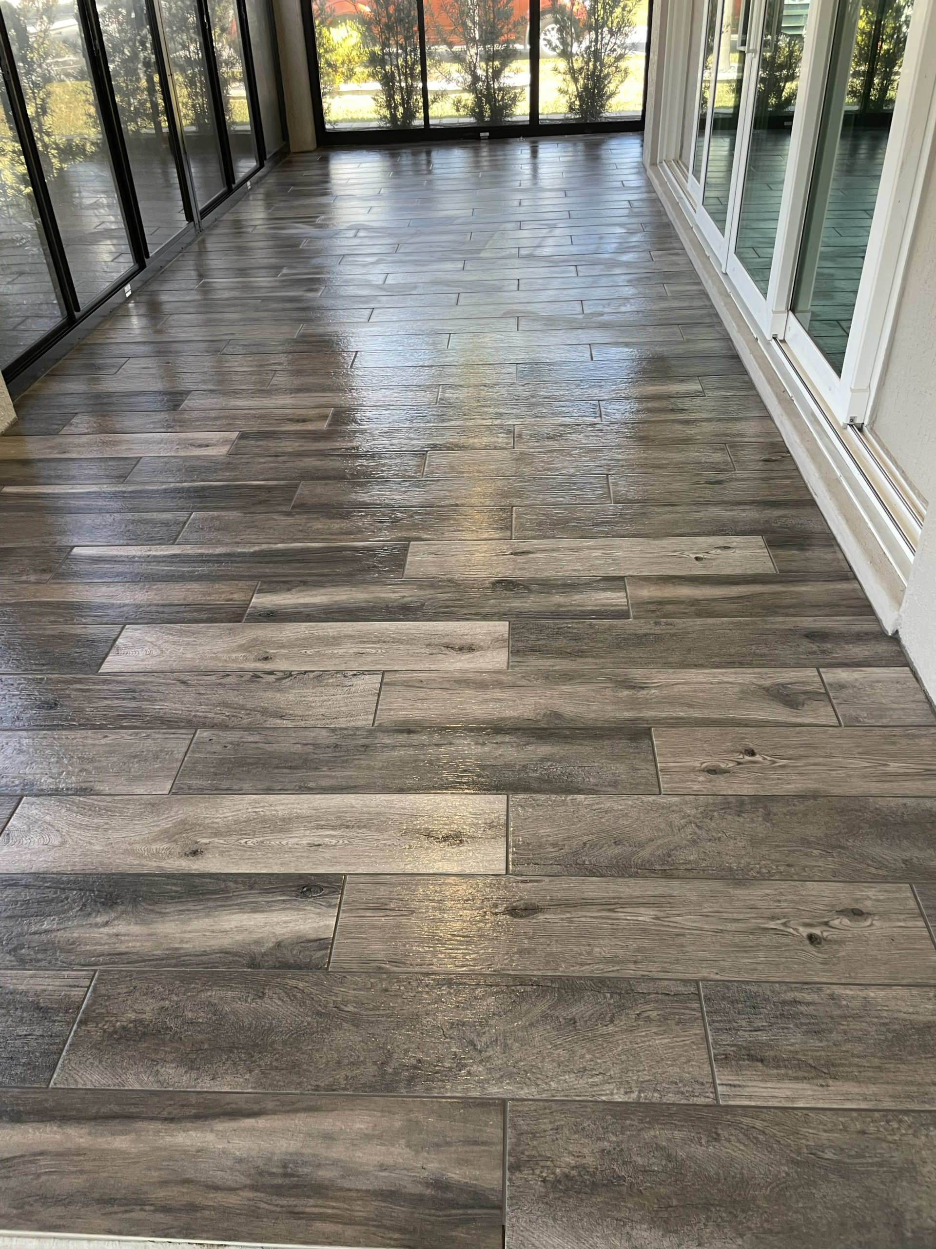 Weathered gray wood-look porcelain tile installation, bringing a seamless rustic indoor feel directly to this outdoor living space.