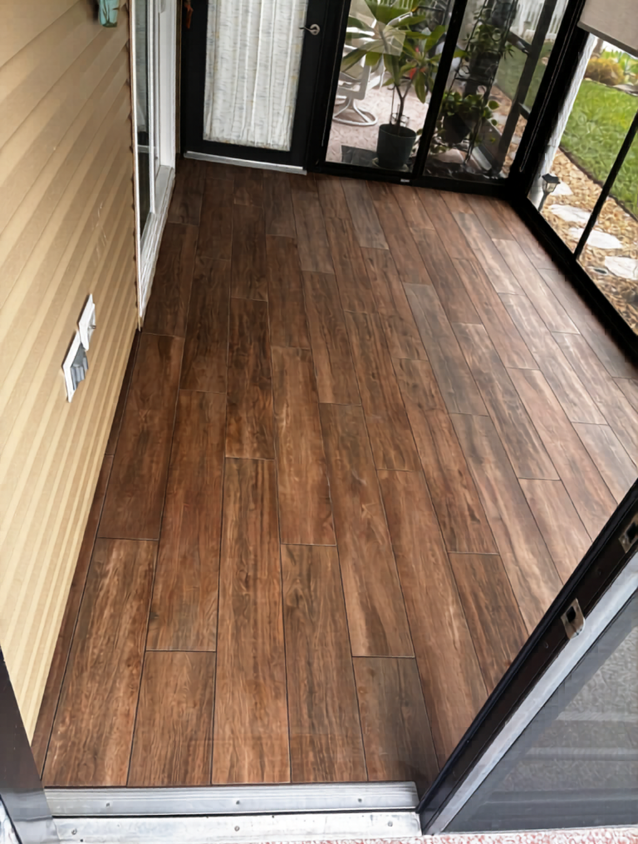 Rich cherry wood-look porcelain tile installation by CRB Services Pro, creating a warm and welcoming screened lanai floor.