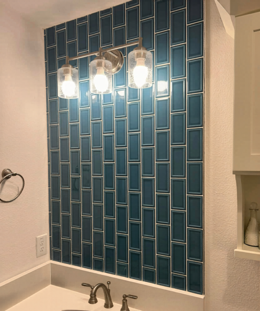 Modern coastal style. This rich teal ceramic tile installation creates a stunning, light-reflective focal point for a bathroom vanity area.