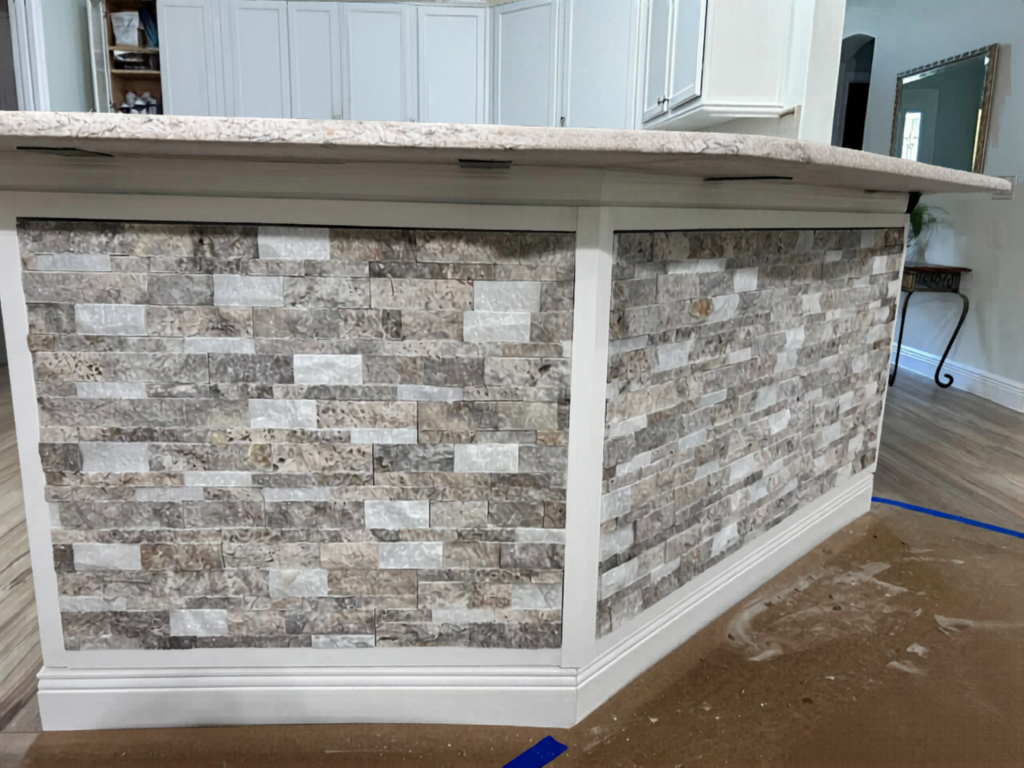  Custom-framed ledger stone panels add rugged texture and custom architectural craftsman styling to a standard kitchen island bar.