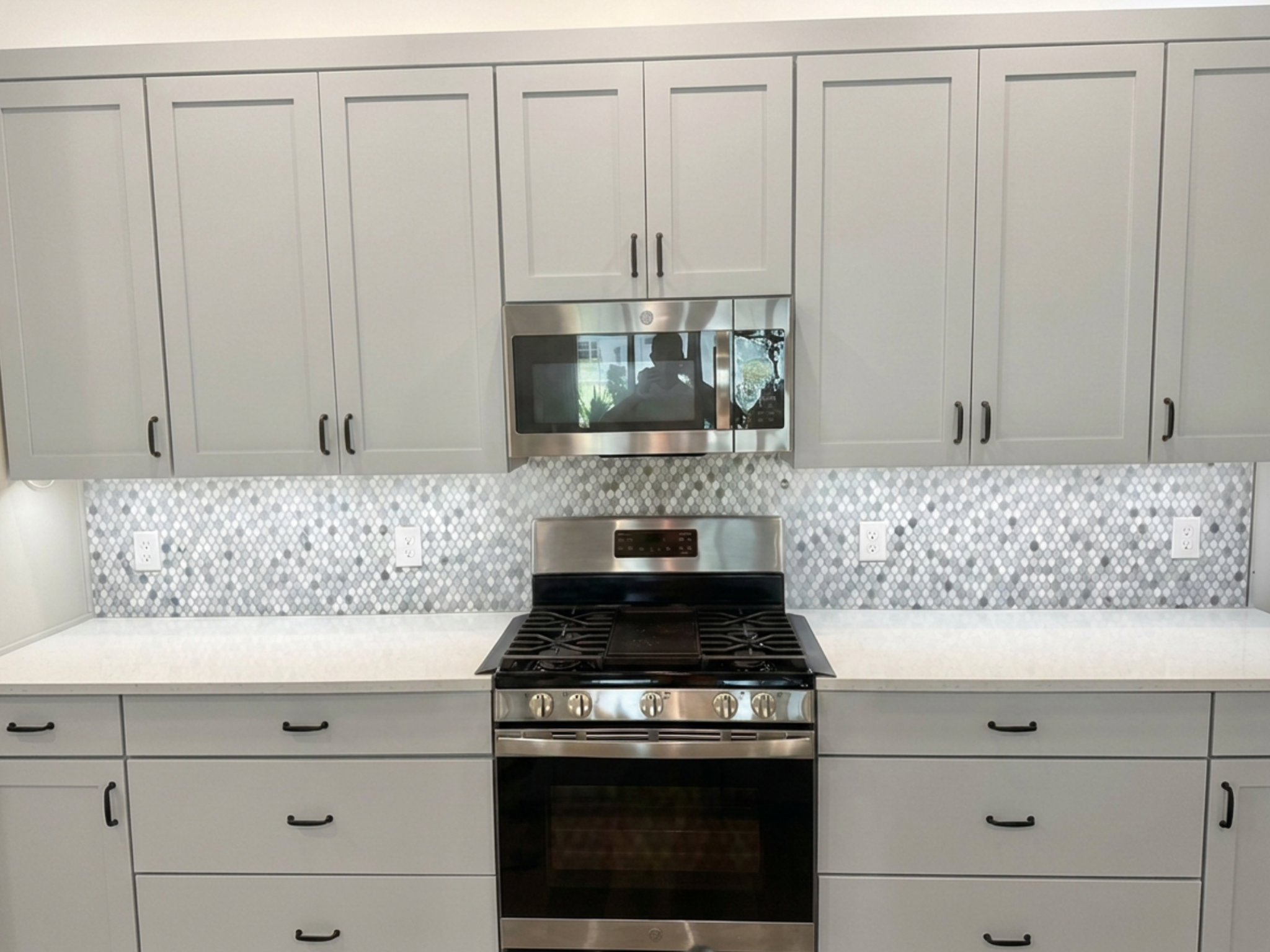 Modern kitchen range with multi-toned gray marble hexagon mosaic tile backsplash by CRB Services Pro in The Villages FL.