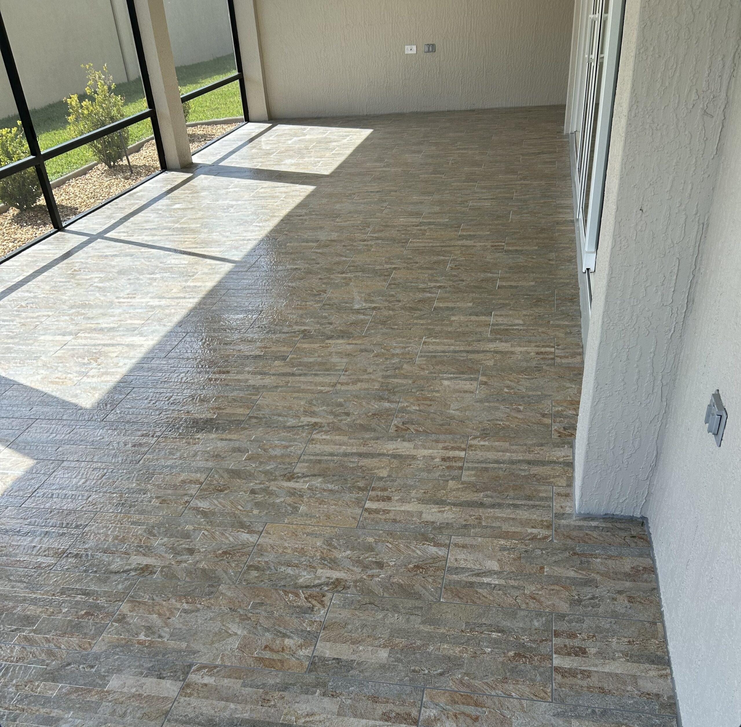 This modern porcelain tile installation transforms this screened lanai into a stylish extension of the home. Installed with meticulous attention to detail, the clean lines and natural color variations create an inviting space for relaxing and entertaining year-round.
