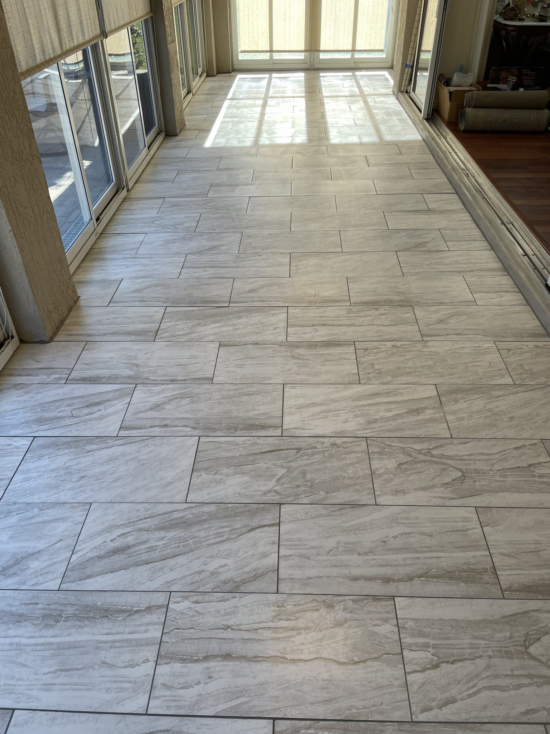 Enjoy the warmth of hardwood with the durability of porcelain tile. This wood-look tile installation offers the beauty of natural wood without the maintenance, making it an ideal choice for screened lanais and covered outdoor living spaces.