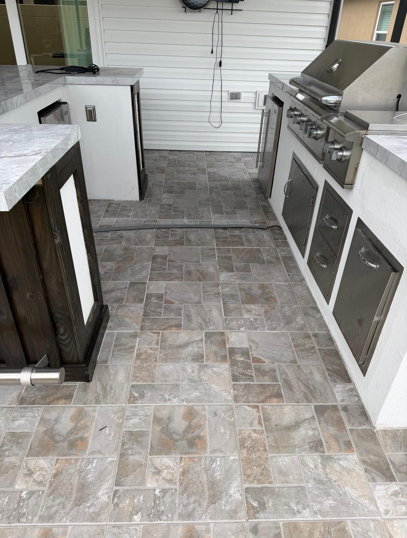 Complete Outdoor Living Space
Attention to detail is evident throughout this custom outdoor kitchen area, where the tile installation flows seamlessly around cabinets, appliances, and walkways. Every cut and transition was completed with precision to create a polished, high-end finish that ties the entire space together.